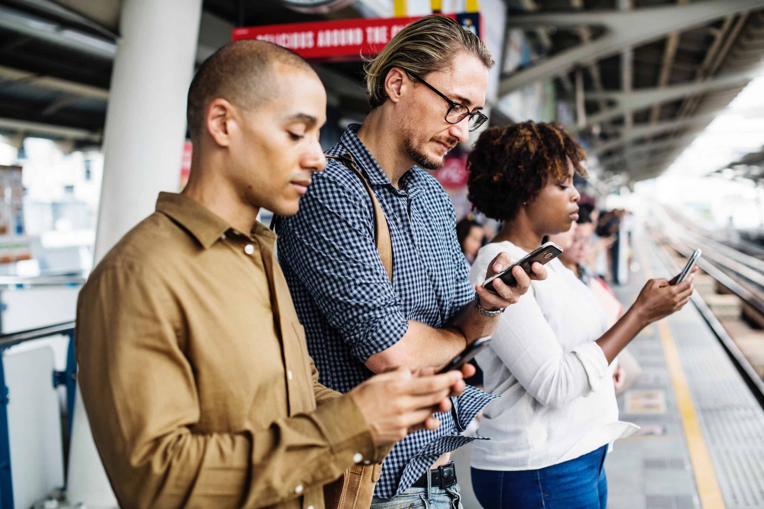 people on their phones waiting for train